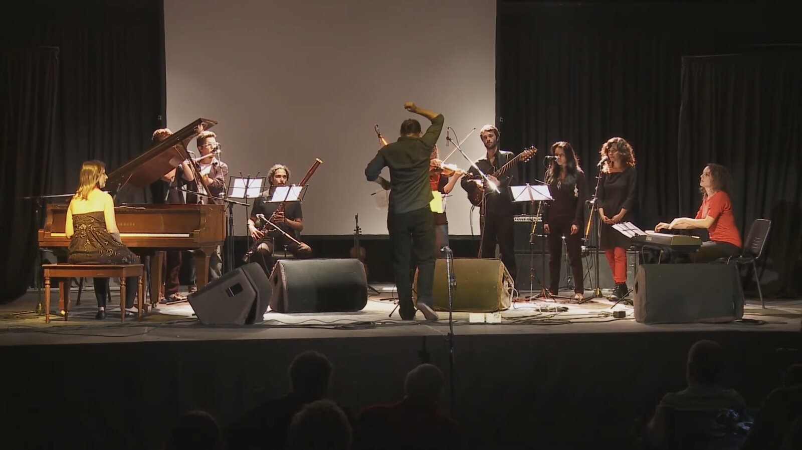 Ensamble Argentino de Improvisadores in concert, the conductor giving a cue