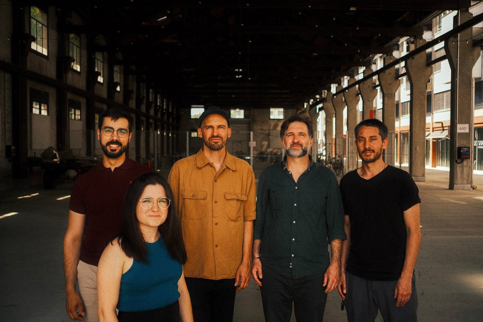 The five members of Slide Ensemble standing in a large industrial hall