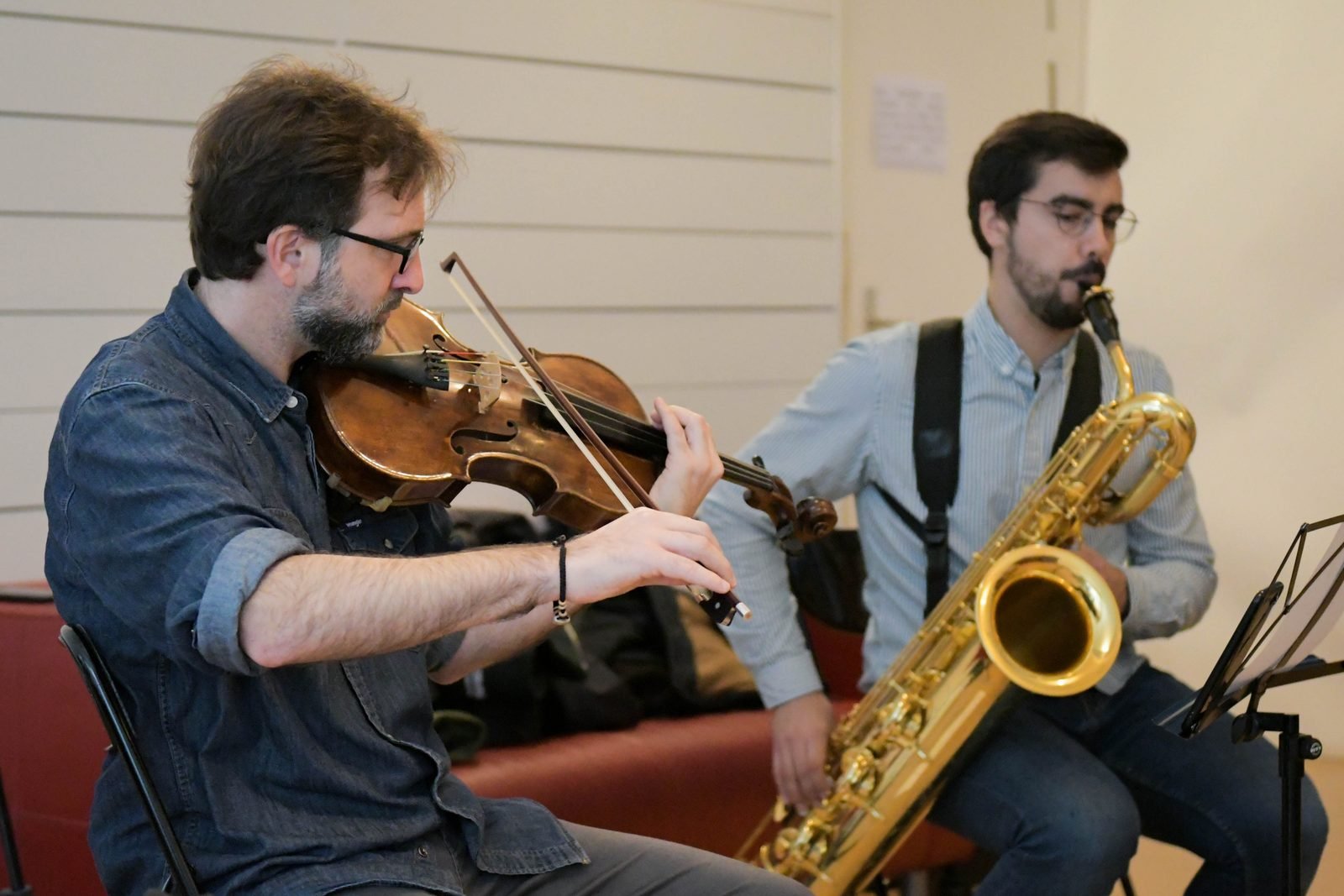 Diego Kohn on violin and a baritone saxophonist in rehearsal
