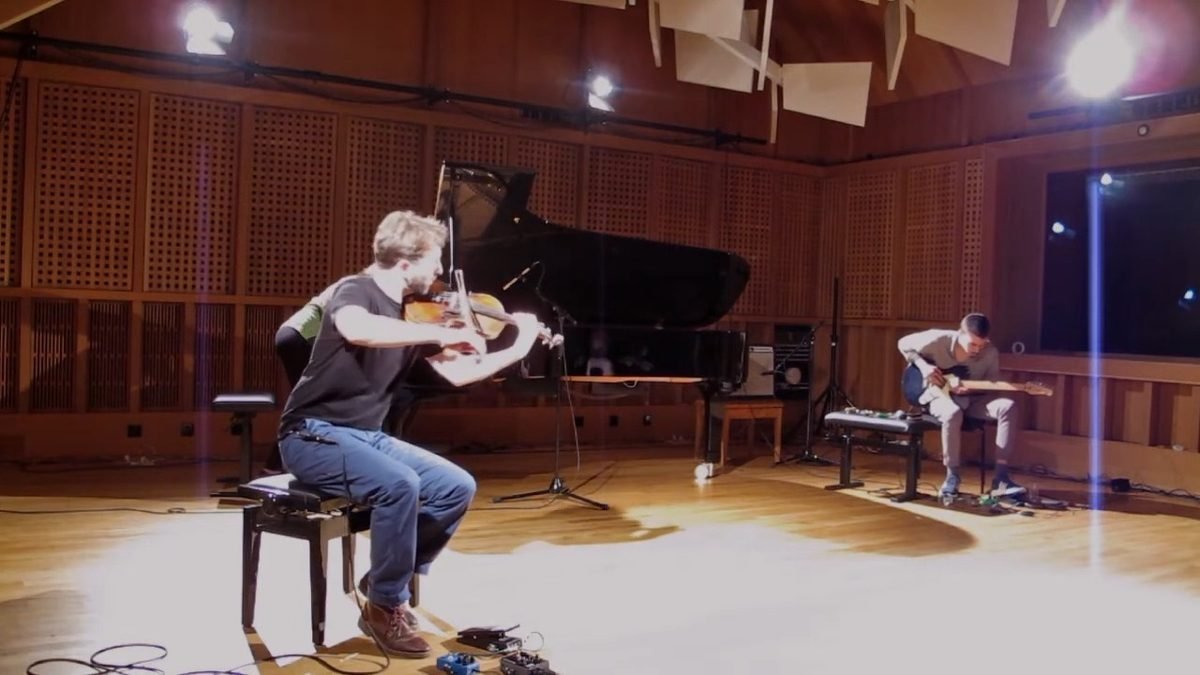 Diego Kohn playing violin in the trio, piano and guitar behind