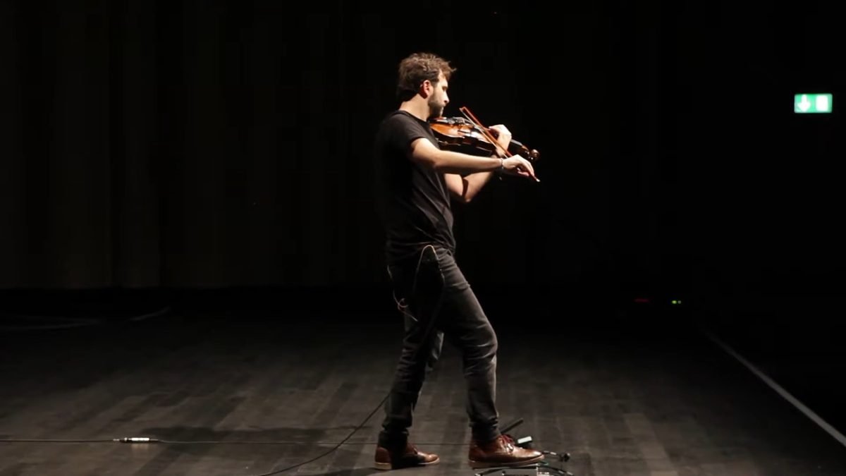 Diego Kohn in profile, stepping forward while playing violin