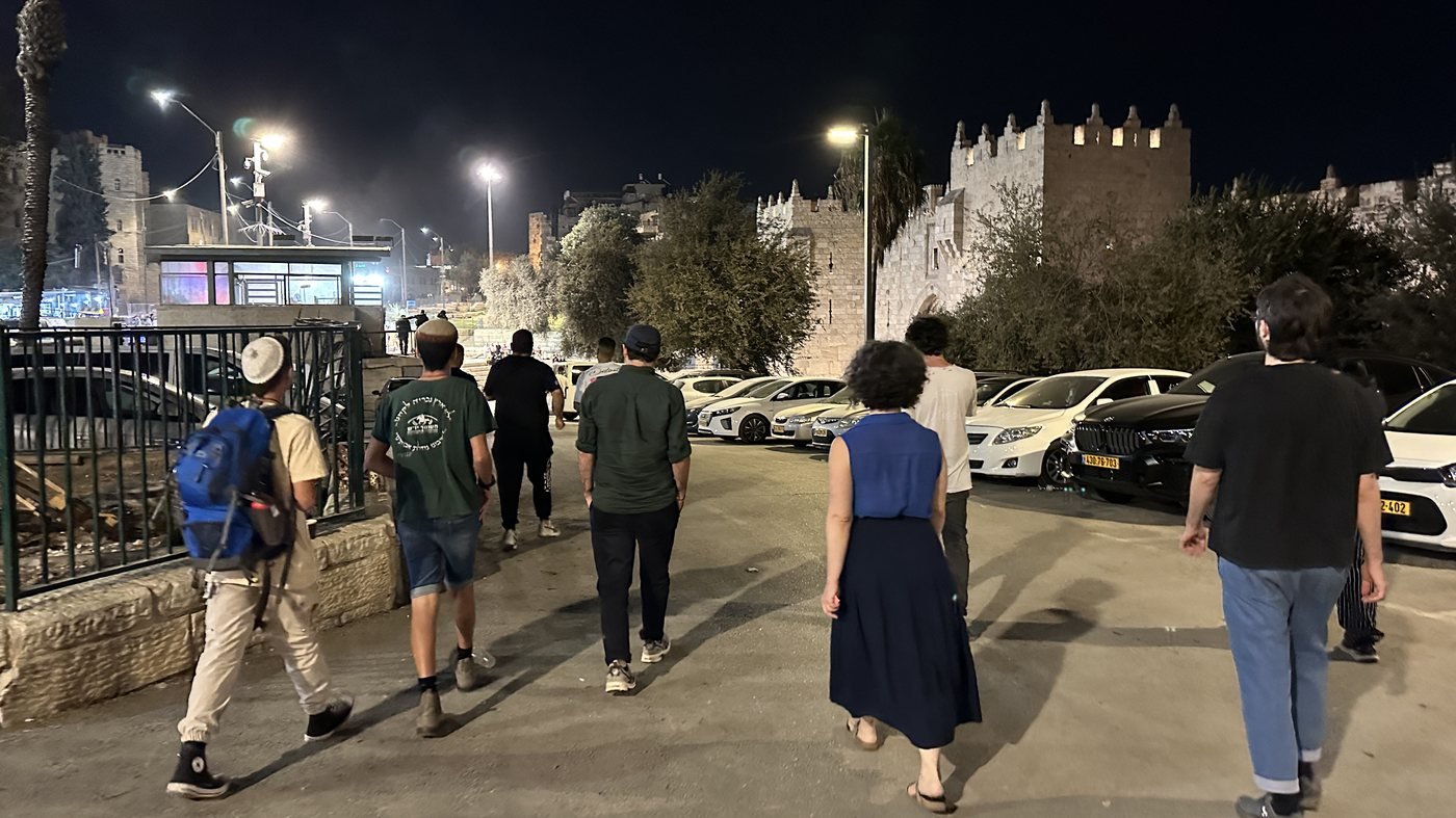 Workshop participants walking along a street outside the Old City walls of Jerusalem at night